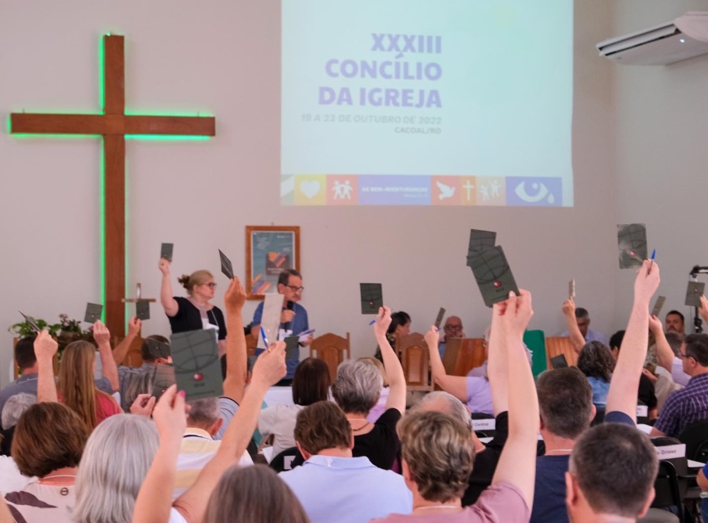 Pessoas levantando folhetos dentro da igreja, de frente para o pastor
