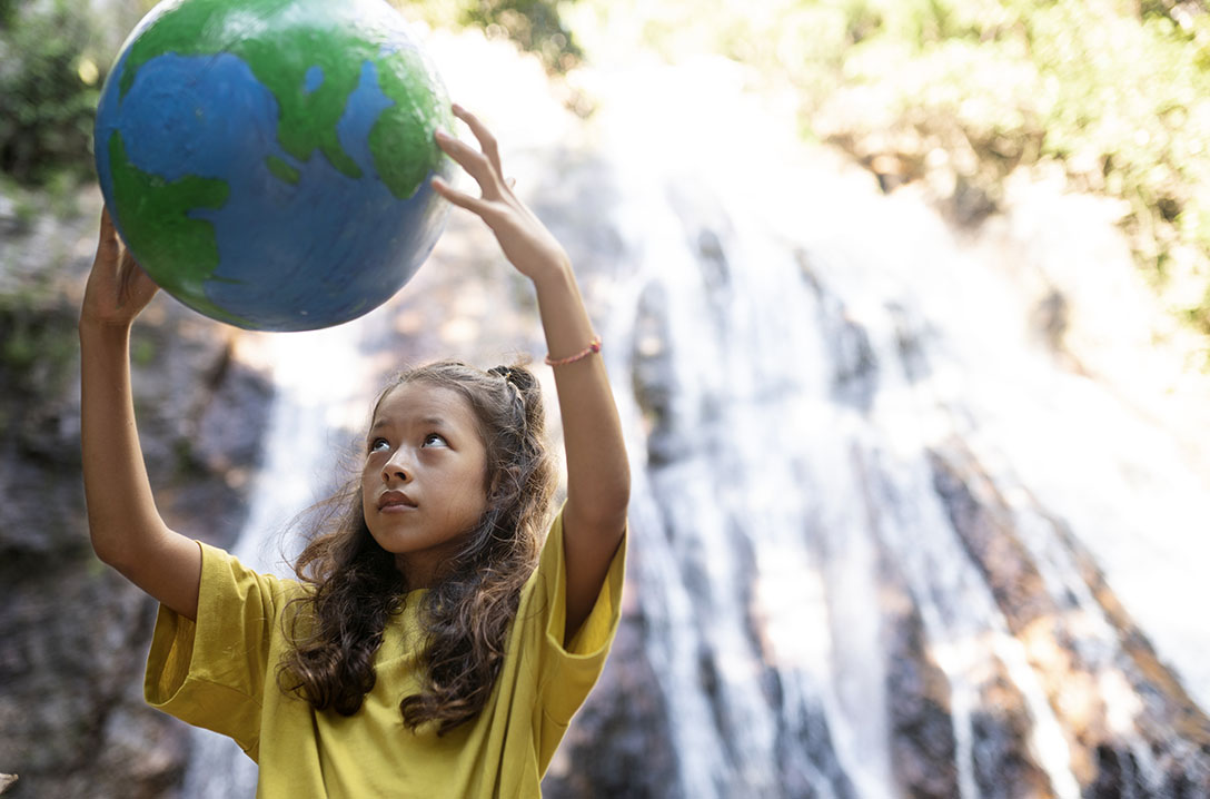 Menina segurando o planeta terra com cachoeira ao fundo