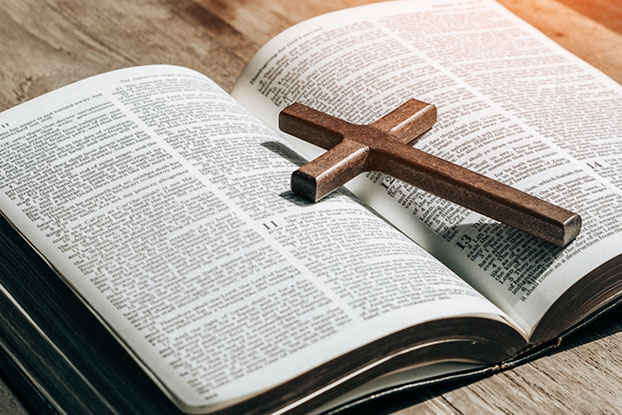 Pequena cruz de madeira em cima de uma bíblia aberta